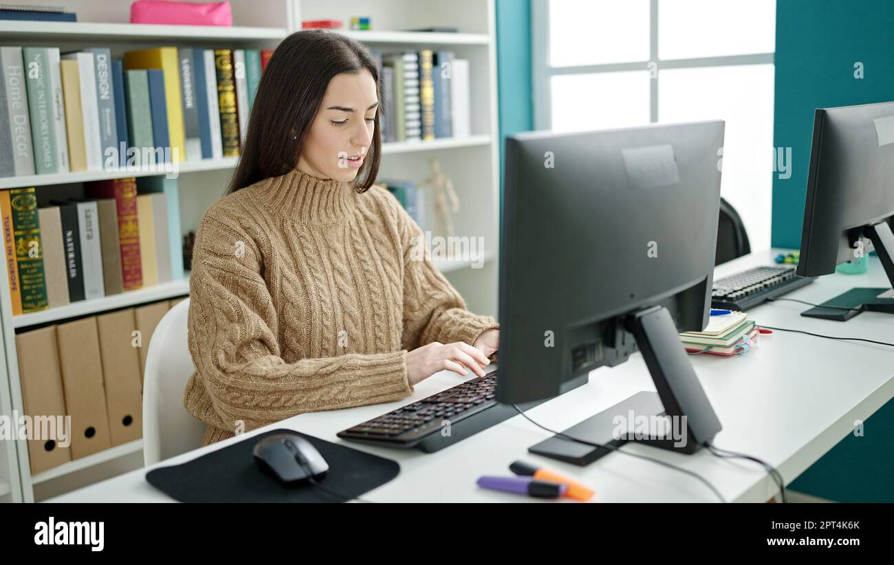 Jeune belle femme hispanique étudiant utilisant un ordinateur avec une expression sérieuse dans la classe d'université Banque D'Images