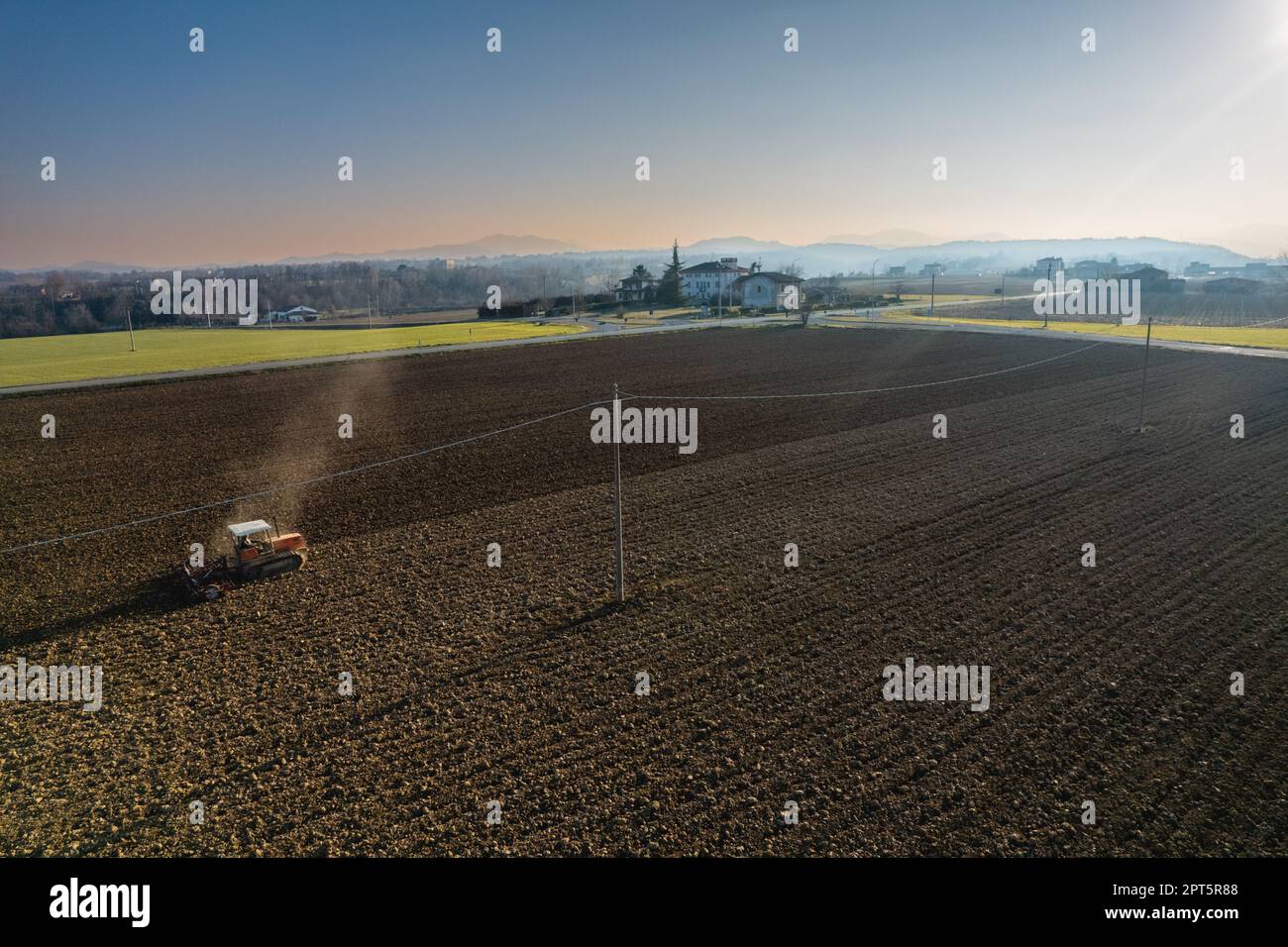 un agriculteur qui conduit un tracteur à chenilles tire un nuage de poussière derrière lui, labour, casse-croûte de surface de hersage pour faciliter la naissance et l'ensemencement o Banque D'Images