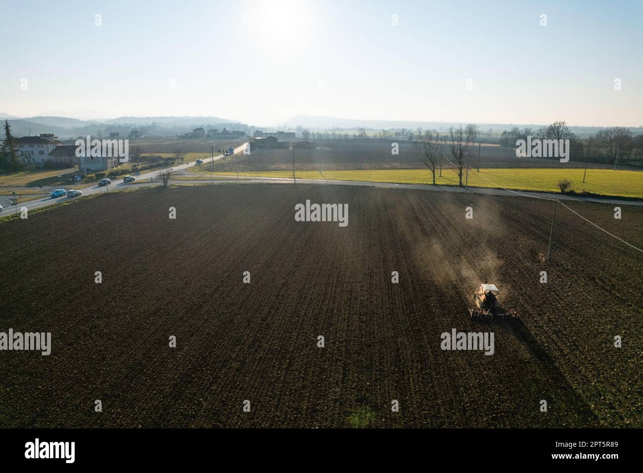 un agriculteur qui conduit un tracteur à chenilles tire un nuage de poussière derrière lui, labour, casse-croûte de surface de hersage pour faciliter la naissance et l'ensemencement o Banque D'Images