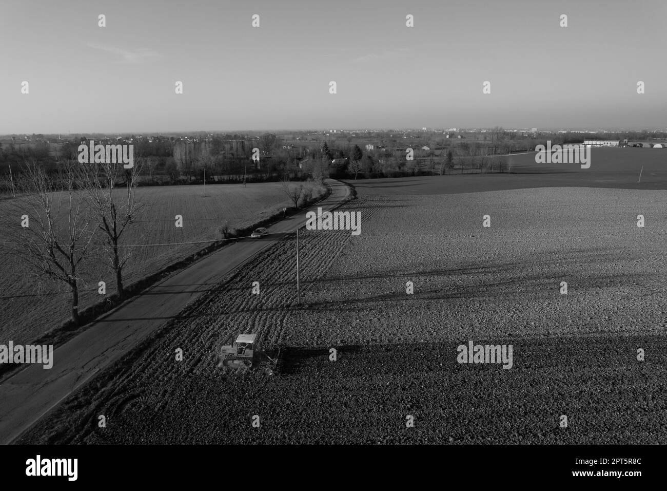 un agriculteur qui conduit un tracteur à chenilles tire un nuage de poussière derrière lui, labour, casse-croûte de surface de hersage pour faciliter la naissance et l'ensemencement o Banque D'Images