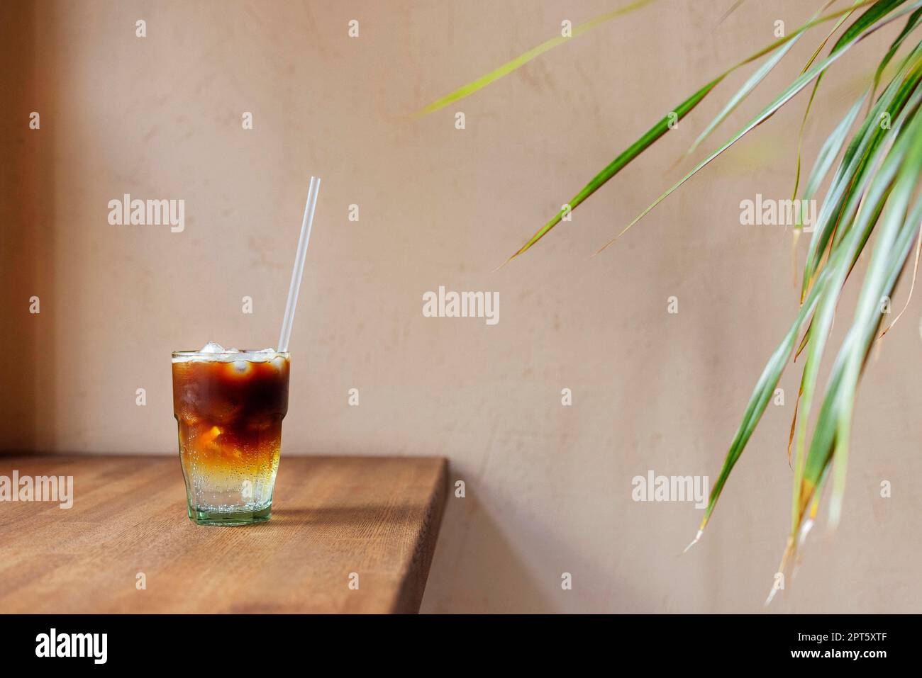 Café glacé à l'orange. Verre d'americano mélangé avec du soda artisanal et du jus d'orange yuzu sur fond flou, concept rafraîchissant de boisson d'été Banque D'Images