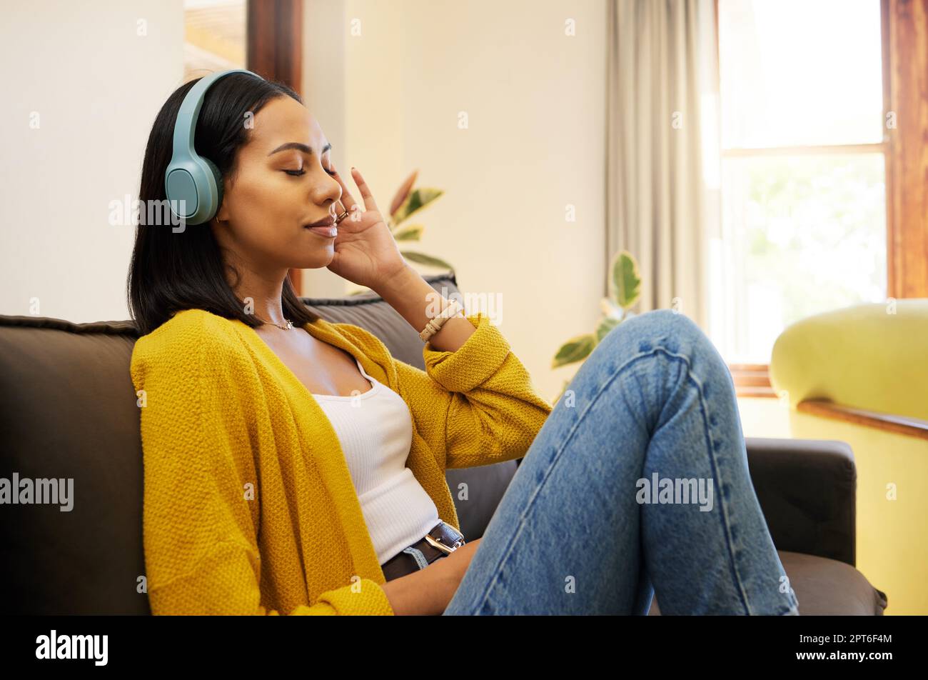 Femme, musique et se détendre avec un casque sur le canapé du salon en  profitant de la détente calme à la maison. Jeune femme se détendant sur un  canapé à l'écoute de