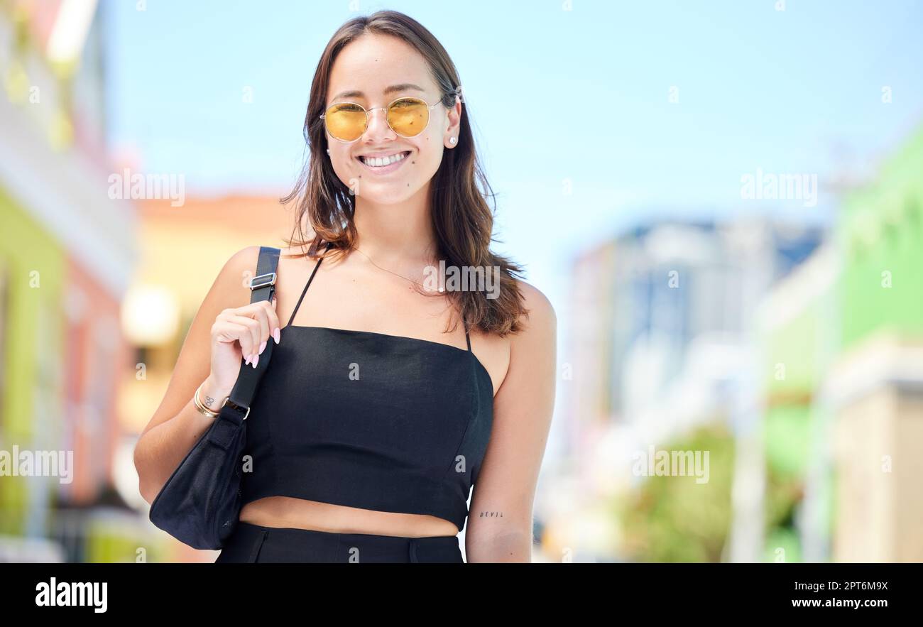 Portrait, femme asiatique et lunettes de soleil avec sourire, heureux et décontracté look dans la ville étant branché, tendance mode et avec sac à main. Jeune fille, détendez-vous et Banque D'Images