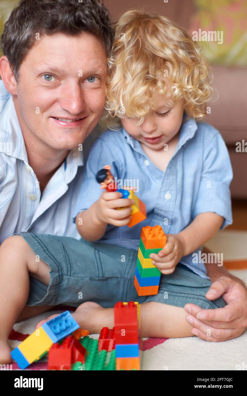 C'est un super tout-petit. Portrait d'un père allongé avec son fils qui joue avec des blocs de construction Banque D'Images