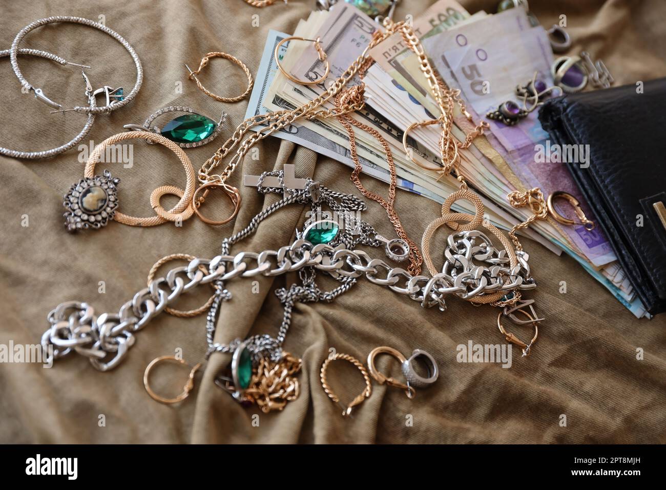 Lot de bijoux volés et d'argent sur tissu militaire uniforme. Pillage par des soldats russes dans les villes ukrainiennes lors de l'attaque russe contre U Banque D'Images