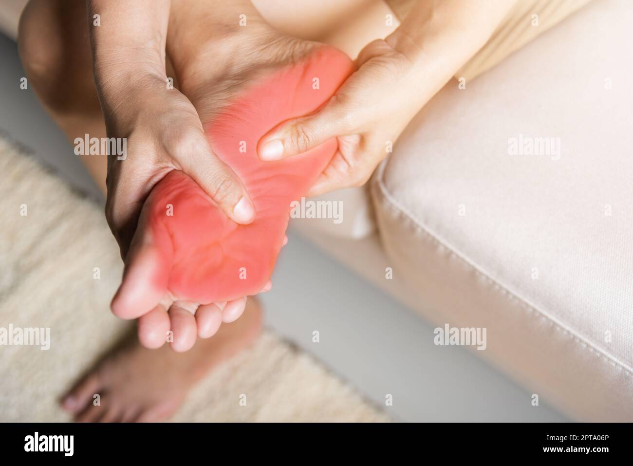 Douleur de pied, femme asiatique assise sur un canapé sentant la douleur dans son pied à la maison, femme souffrant de douleur de pieds utilisation massage de main détendre muscle de la plante en h Banque D'Images