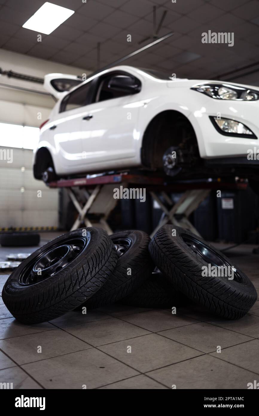 Voiture dans un garage pour l'entretien, l'huile, le changement de pneu (DOF peu profond; image colorée) Banque D'Images