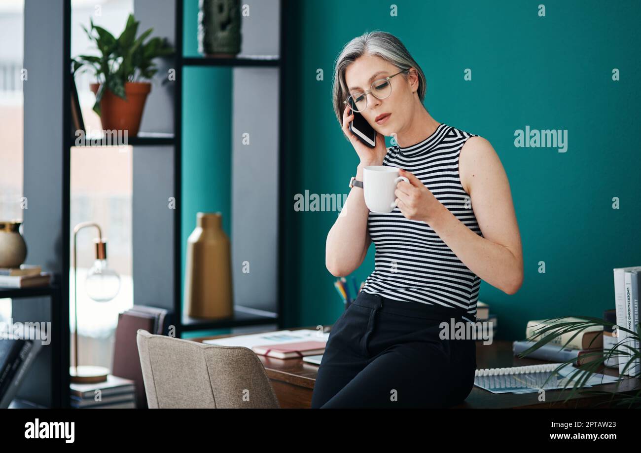 Prendre un café tout en discutant des affaires. une femme d'affaires prenant un café tout en parlant sur son téléphone portable dans son bureau Banque D'Images