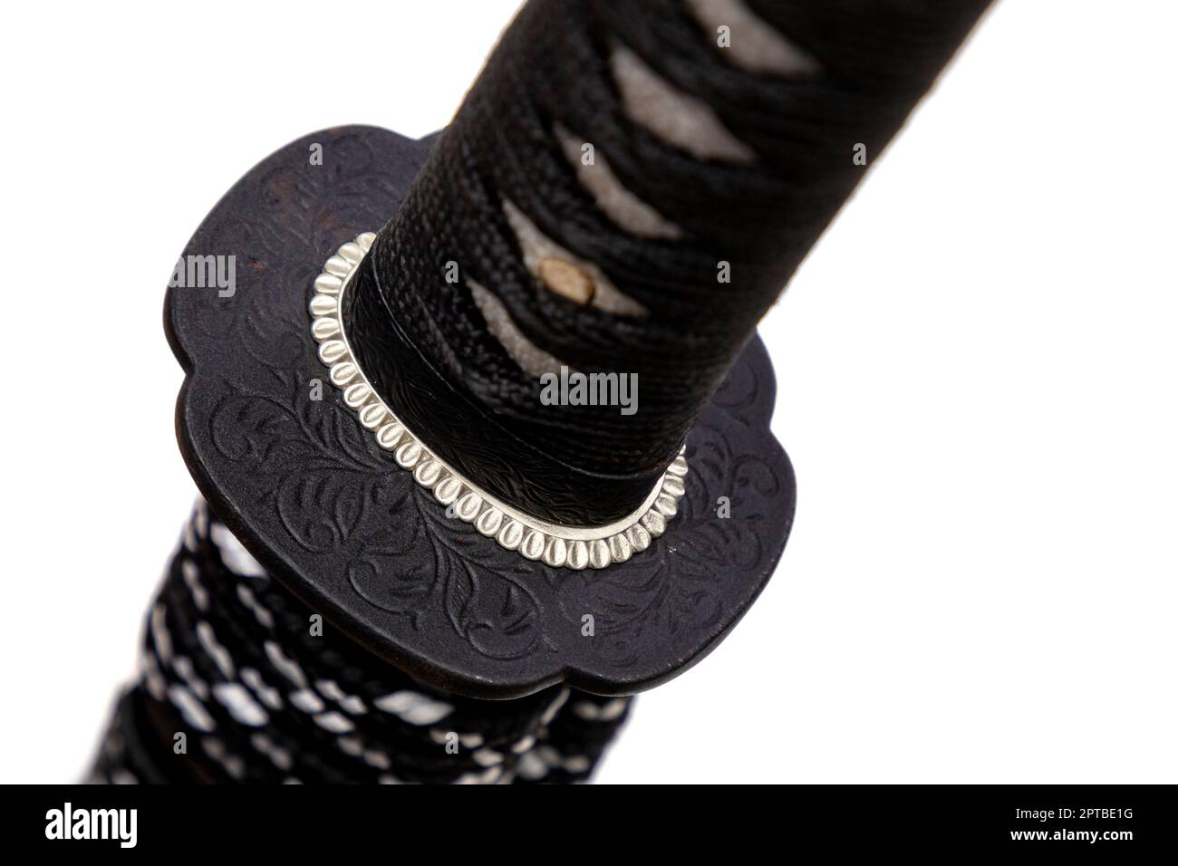 Gros plan de Tsuba - main de garde de l'épée japonaise en acier isolé sur fond blanc. La poignée de l'épée enveloppée de fil de soie noir et de coup Banque D'Images