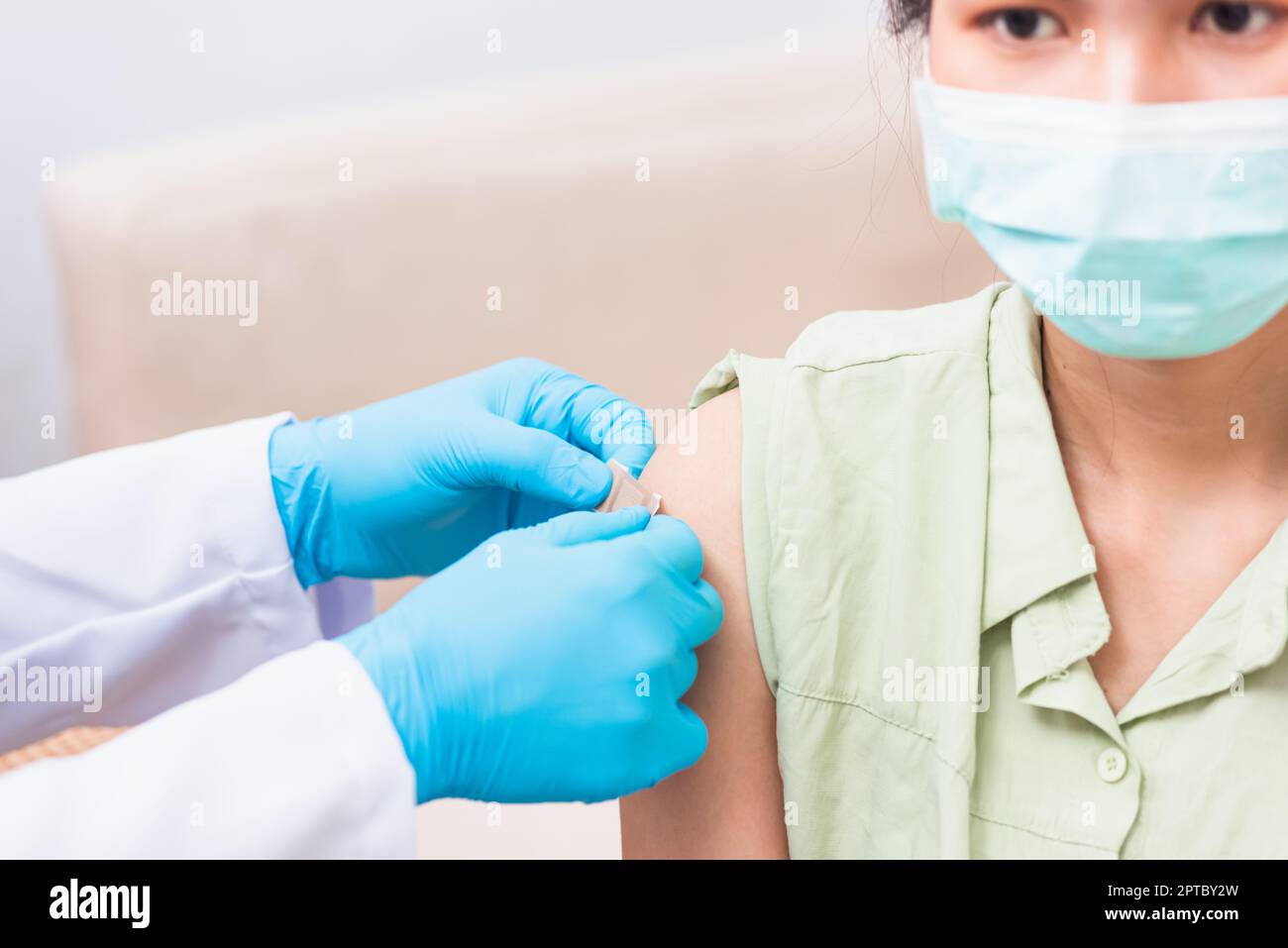 Vaccination, Docteur homme après injection coronavirus vaccin à la jeune femme épaule il caoutchouc gants de protection mettre un pansement adhésif, C Banque D'Images