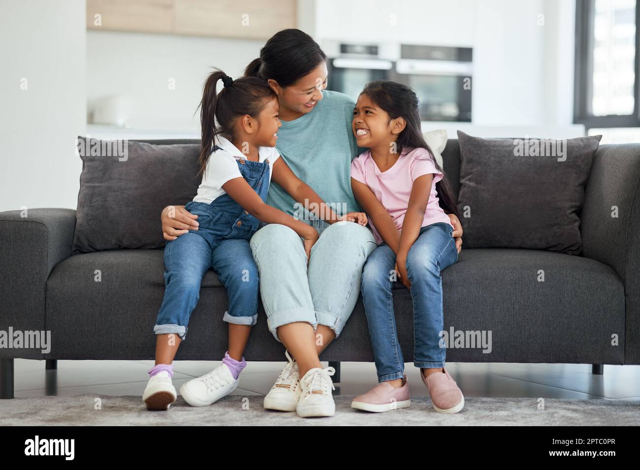 Famille, amour et mère célibataire avec des enfants qui ont l'air heureux, se détendre et sourire assis ensemble et se lier sur le canapé dans le salon à la maison. Baby-sitter asiatique wom Banque D'Images