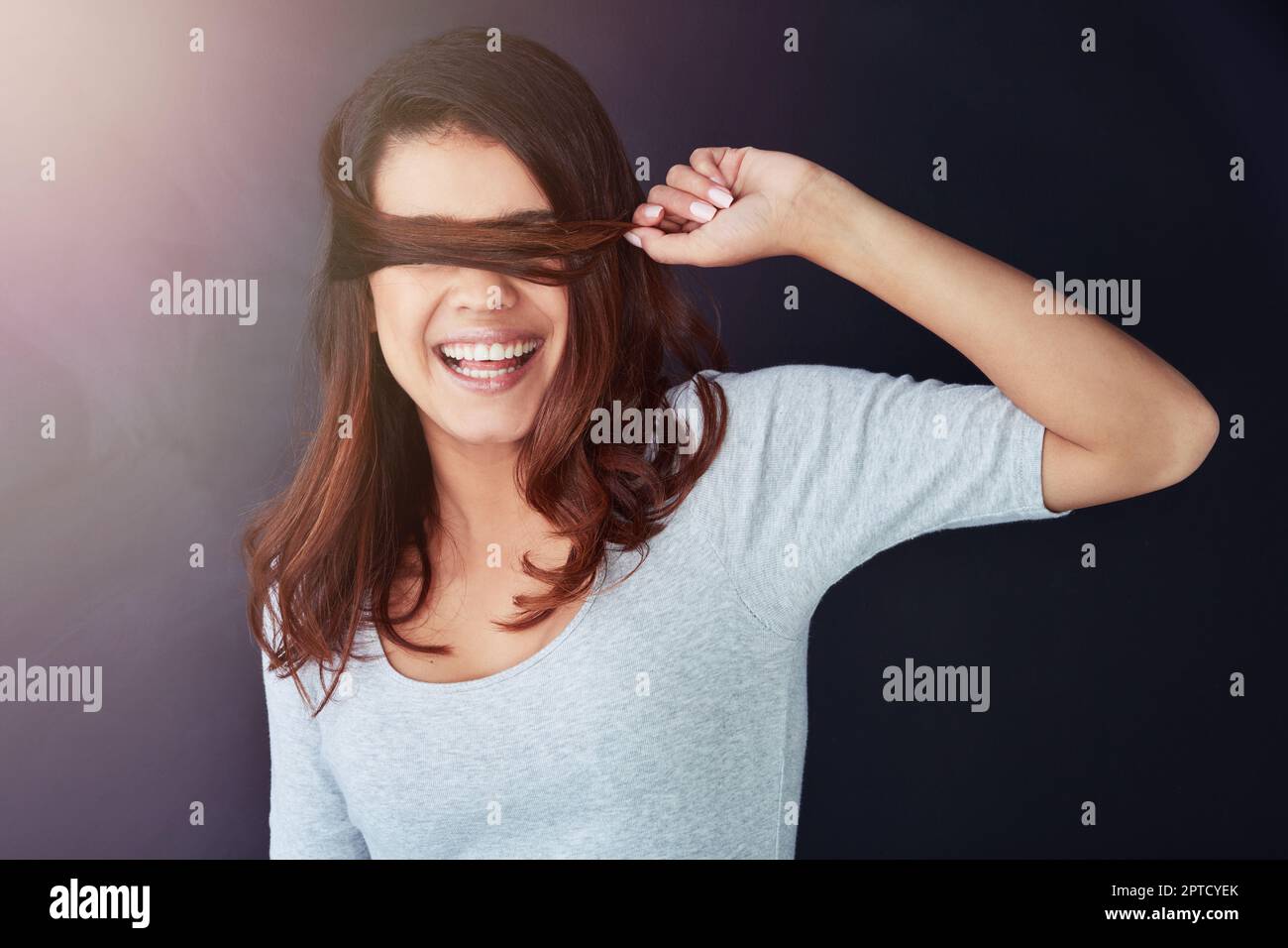 Shes un esprit libre. une belle jeune femme posant avec ses cheveux au-dessus de ses yeux dans le studio Banque D'Images