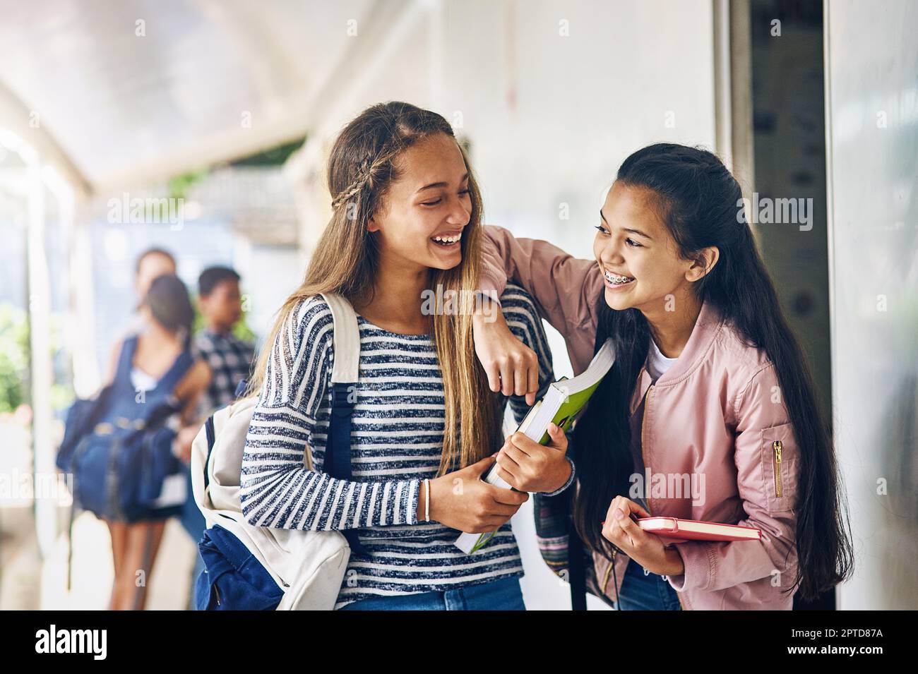 Parfois, les camarades de classe deviennent amis. deux écolières joyeuses bavardant dans le couloir à l'extérieur de leur salle de classe Banque D'Images