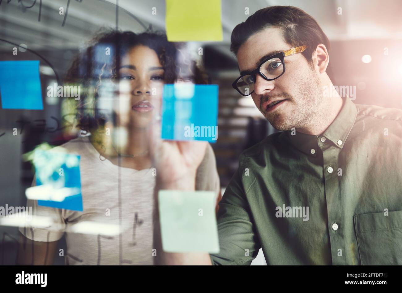 Ceux qui planifient, finissent par réussir. deux jeunes designers planifient sur une planche de verre Banque D'Images