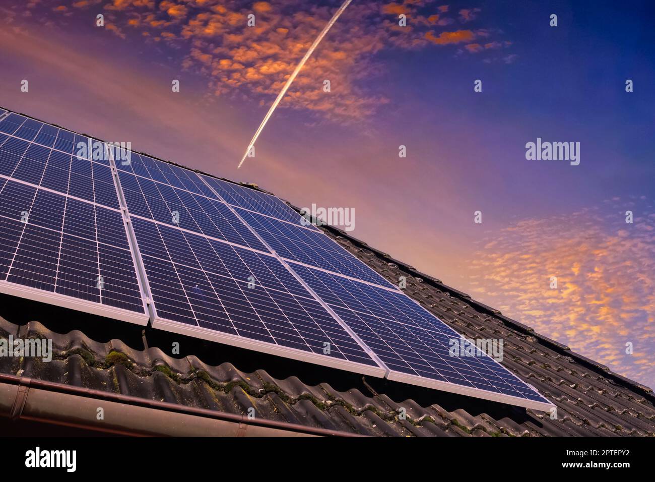 Panneaux solaires produisant de l'énergie propre sur le toit d'une maison résidentielle au coucher du soleil Banque D'Images