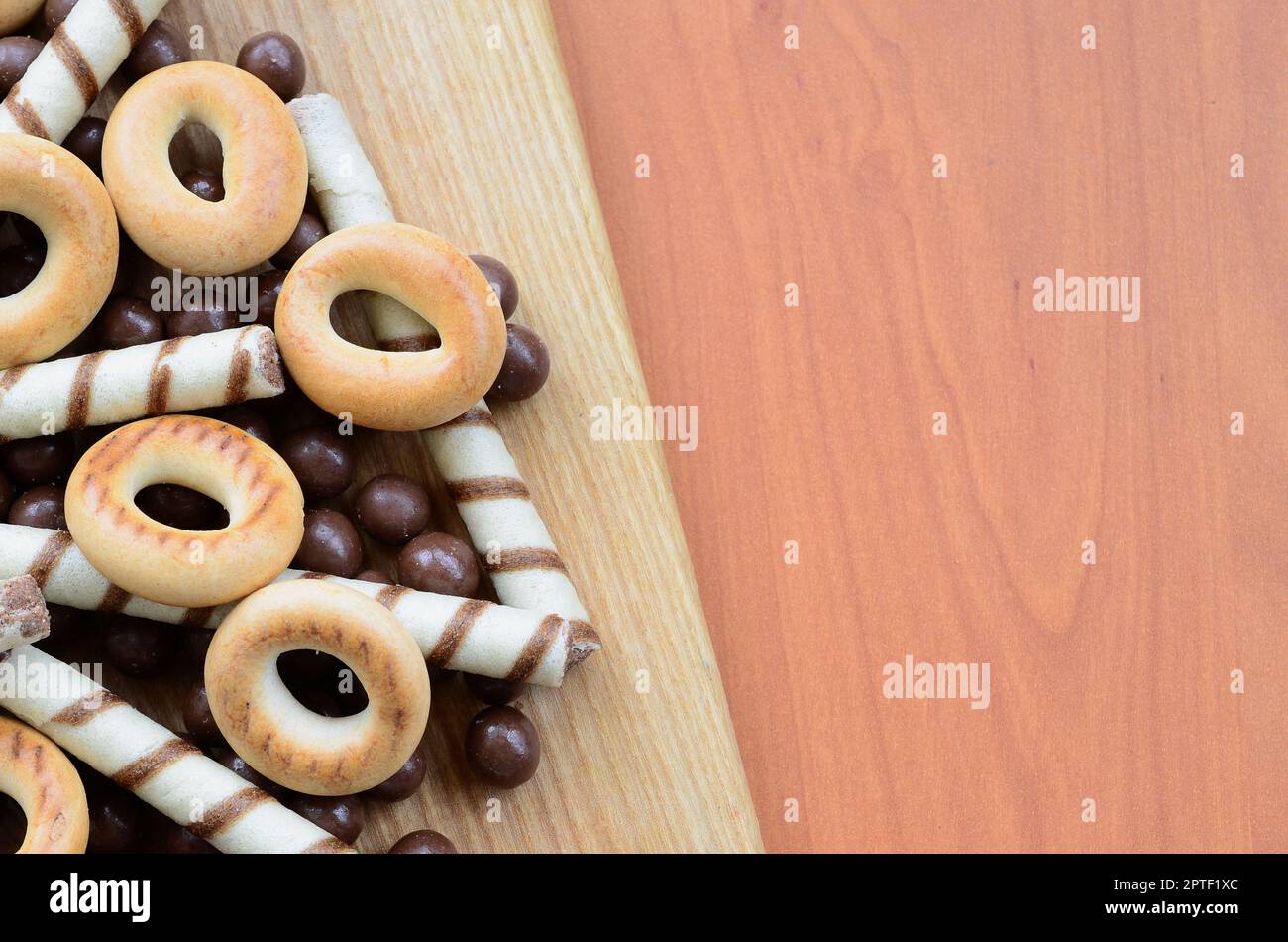 Des tubules croustillants, des boules de chocolat et des bagels se trouvent sur une surface en bois. Mélange de divers bonbons Banque D'Images