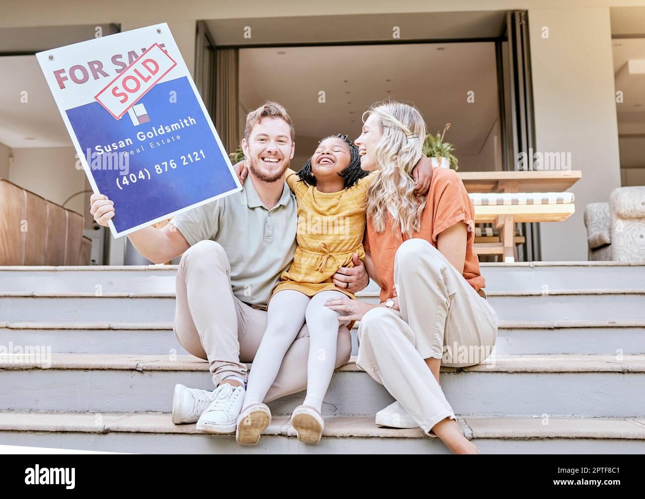 Famille, maison d'achat et signe vendu avec un sourire sur la propriété et la vente de nouveaux biens immobiliers. Portrait d'une affiche émouvante d'un père, d'un enfant et d'un adopter divers Banque D'Images