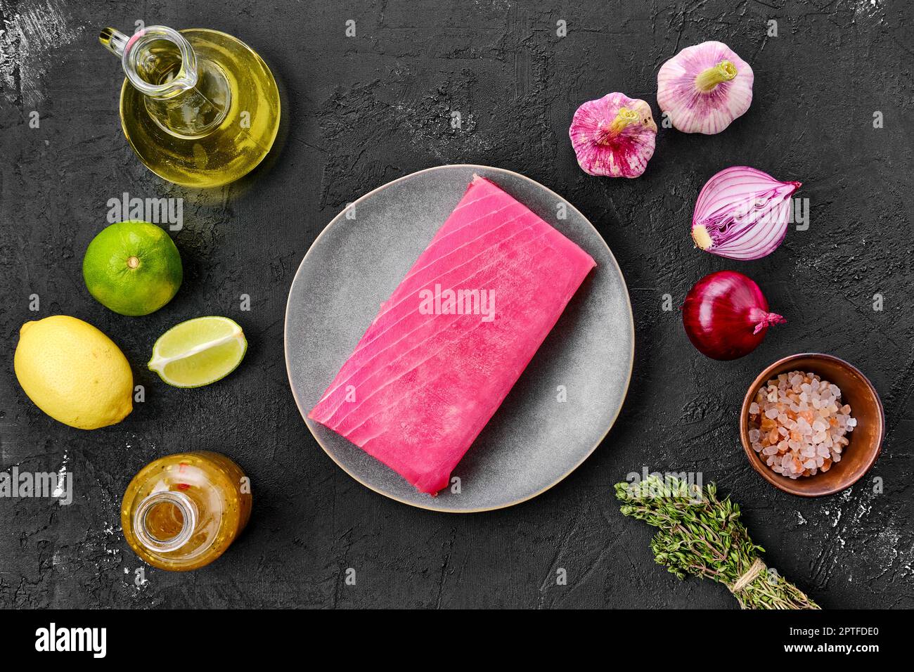 Vue de dessus du filet de thon brut dans l'assiette avec épice sur fond noir Banque D'Images