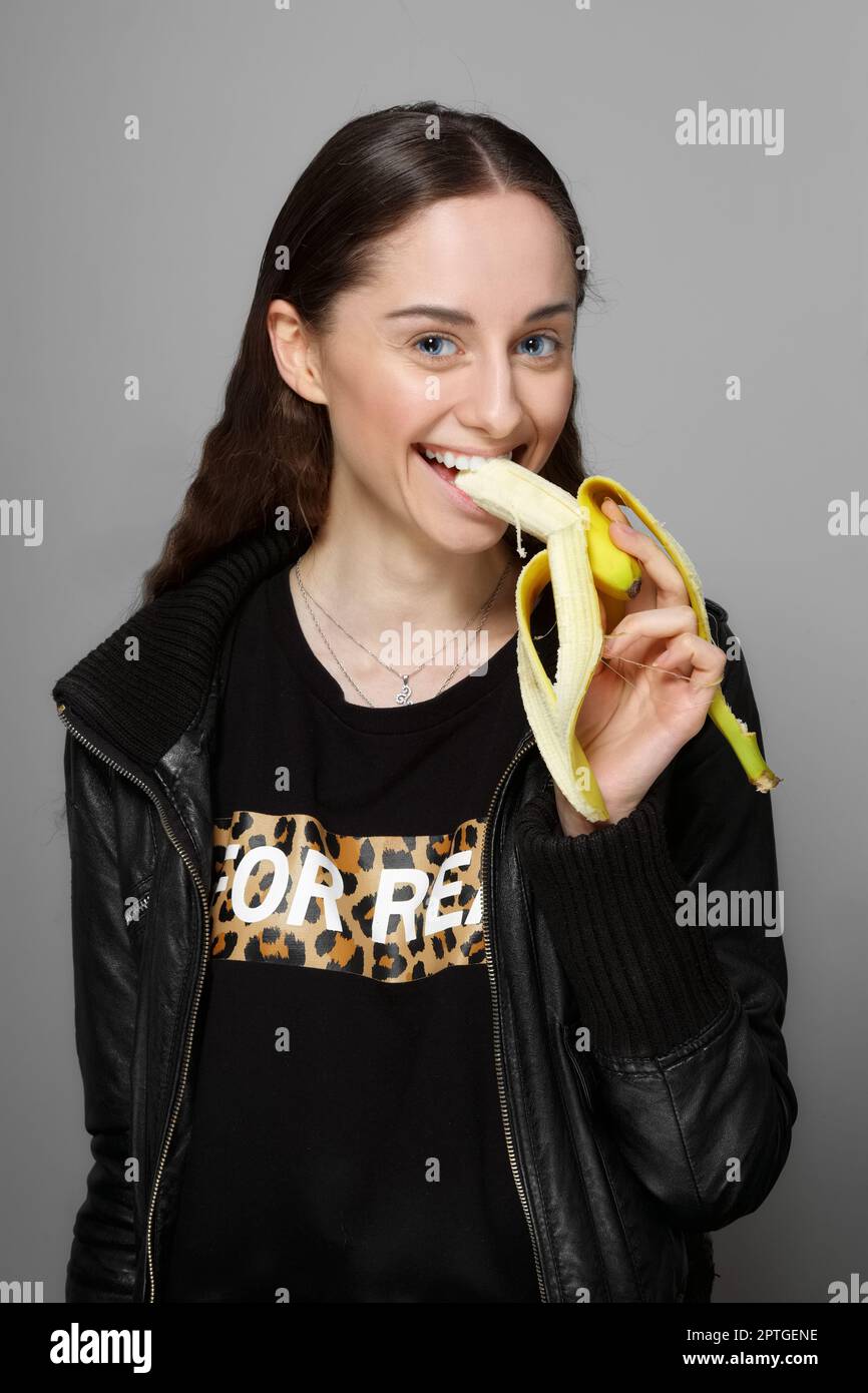 jolie fille en cuir veste morsure banane fraîche. maquillage naturel  propre, cheveux longs, yeux bleus Photo Stock - Alamy