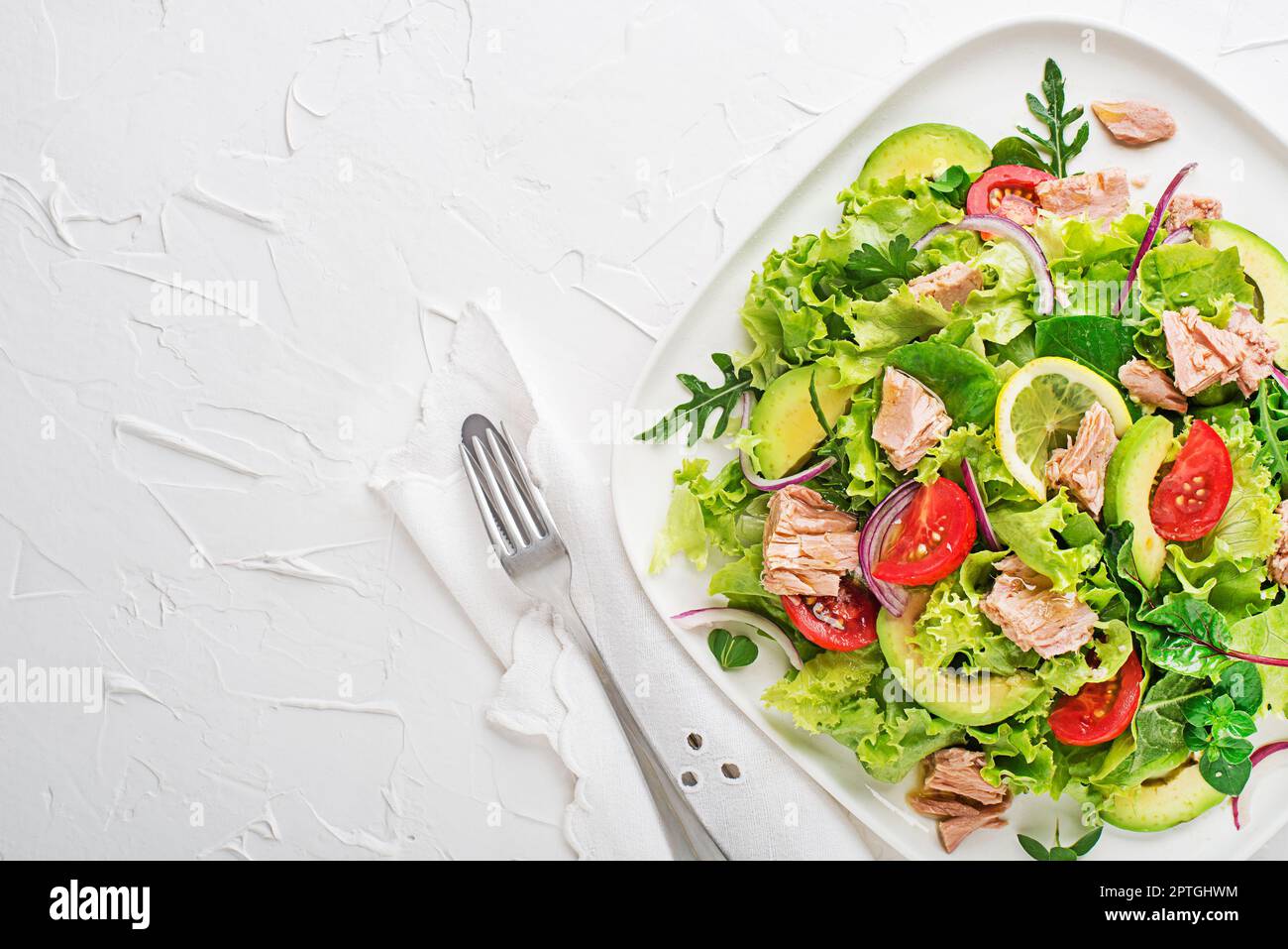 Salade verte fraîche à feuilles d'avocat de thon et de tomate sur fond de table blanc. Concept pour un repas savoureux et sain Banque D'Images