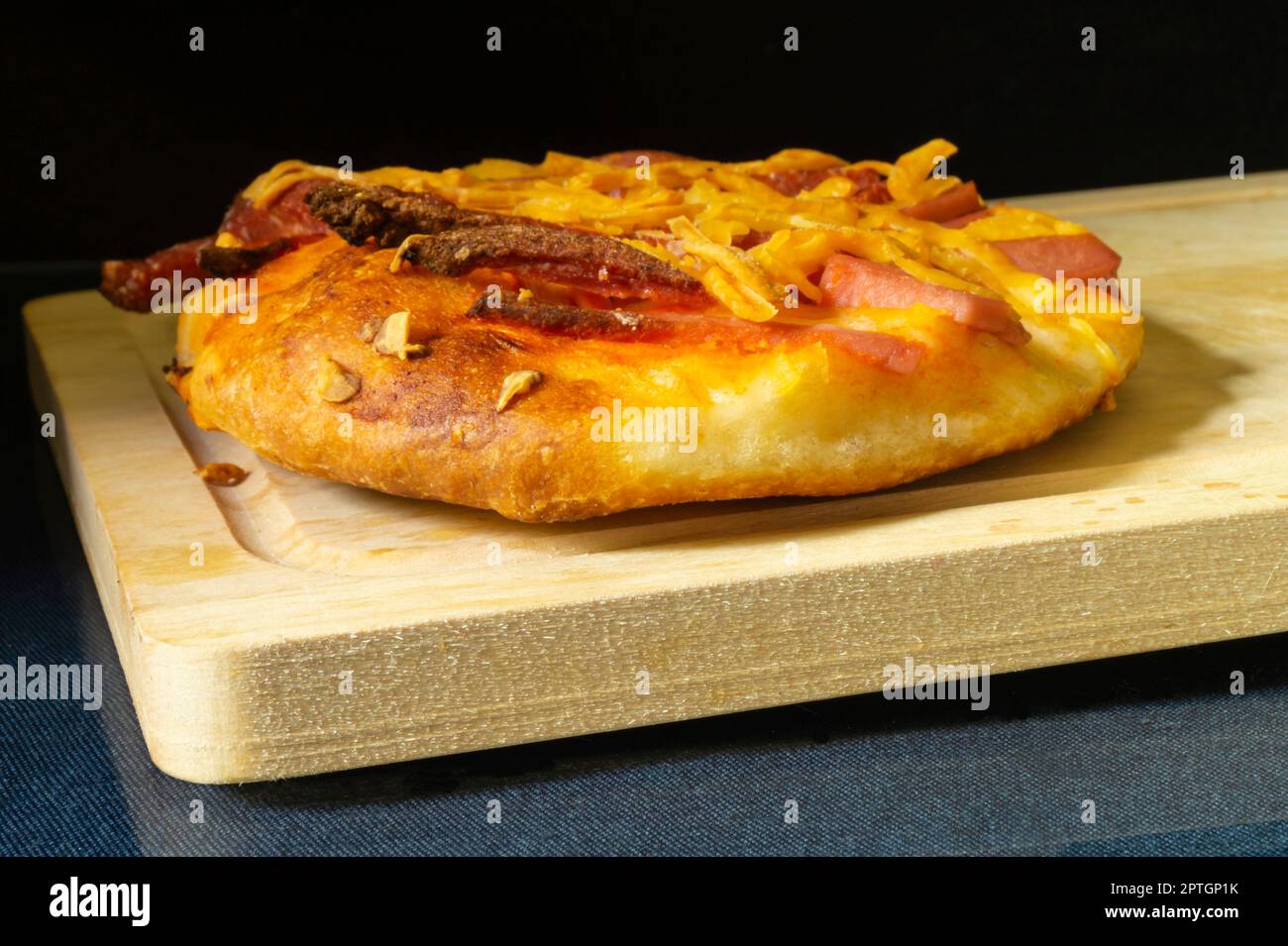 La pizza avec saucisse et fromage sur fond noir. Cuisson sur table. Produits de l'alimentation Banque D'Images