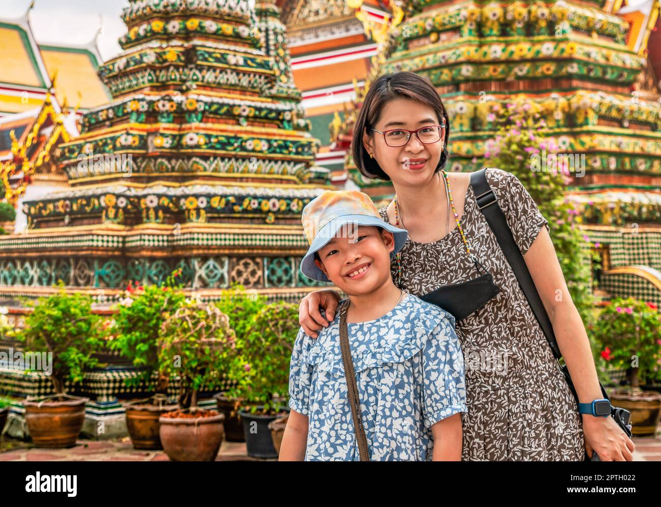 La mère asiatique d'âge moyen et la petite fille voyagent ensemble à Bangkok, Thaïlande, arrière-plan flou de belles stupas dans un temple bouddhiste. Banque D'Images