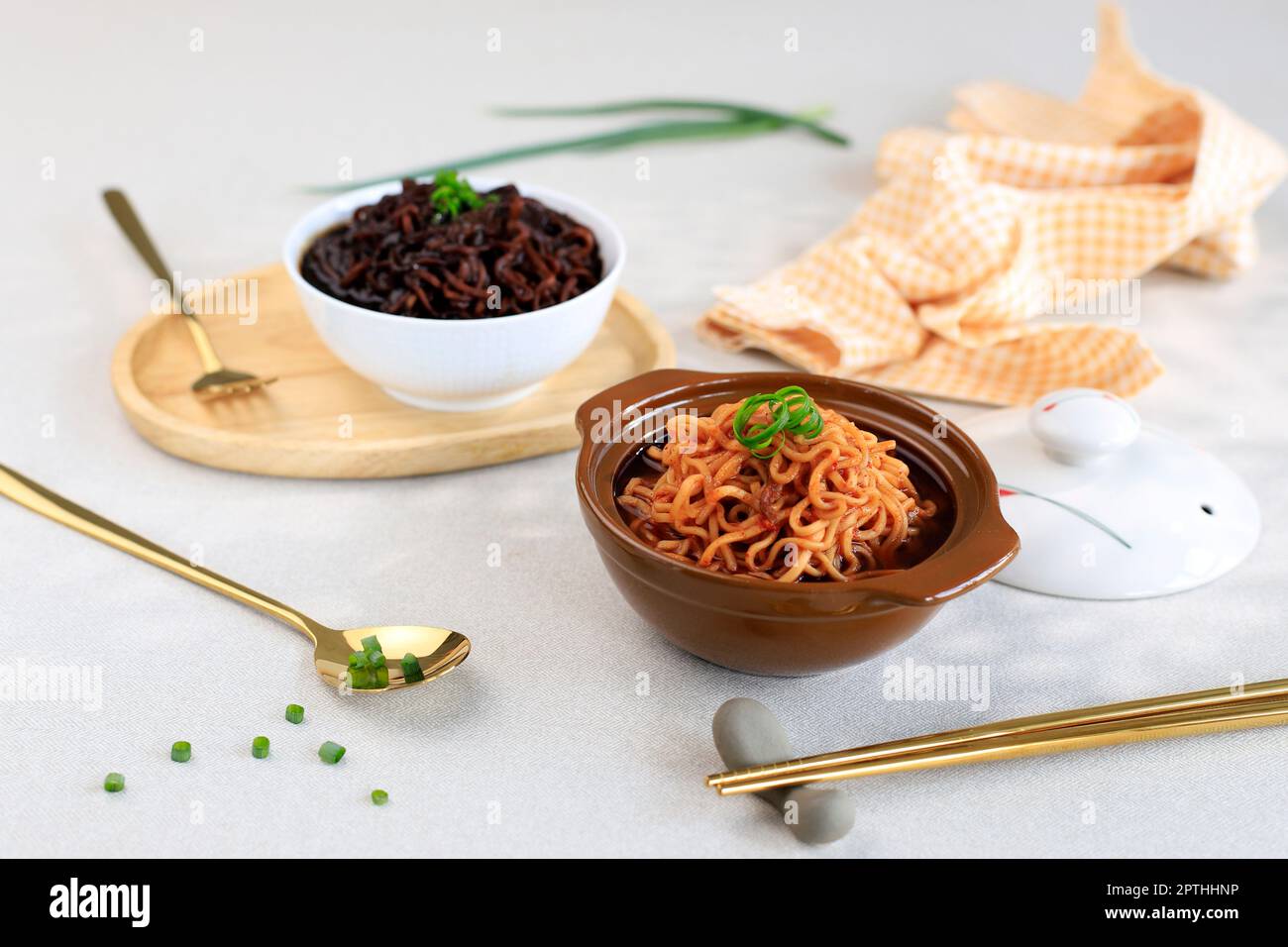 Ramyeon épicé au Kpran et Jjajangmyeon à la sauce noire, servi sur un bol en céramique avec cuillère dorée et fourchette Banque D'Images