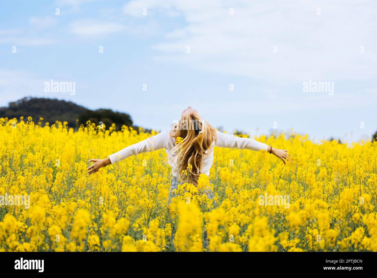 Belle fille aux cheveux blone pose au milieu d'un champ de fleurs de colza jaune Banque D'Images