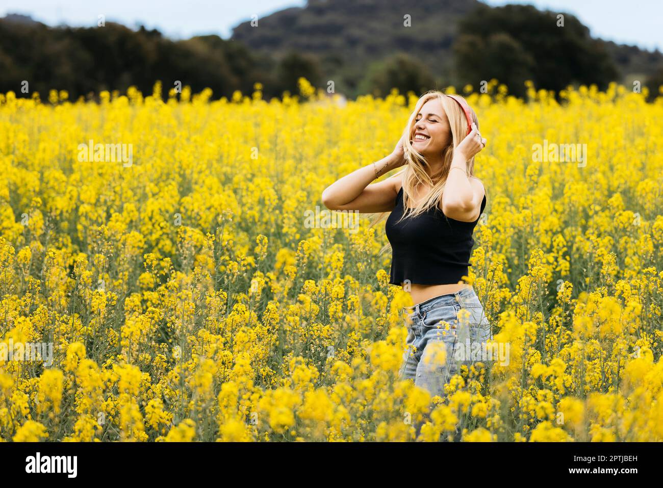 Belle fille aux cheveux blone pose au milieu d'un champ de fleurs de colza jaune Banque D'Images