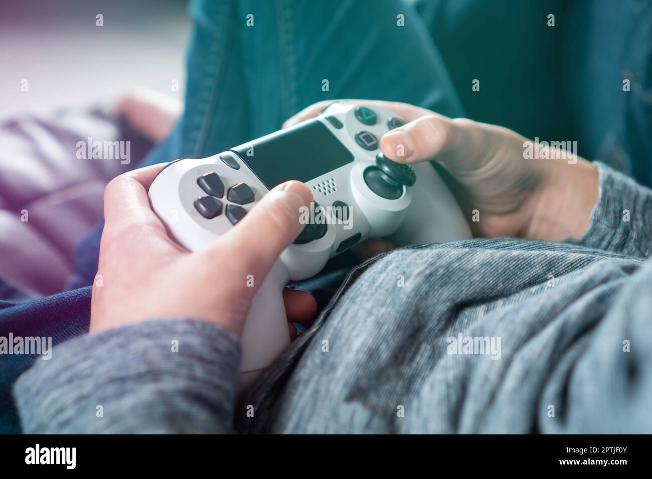 Photo rognée dun adolescent assis à la maison, tenant une manette de jeu blanche, jouant à des jeux vidéo sur la console