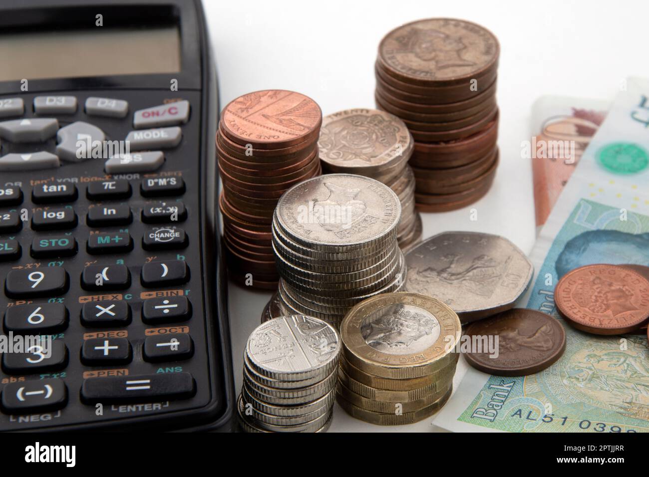Piles de pièces et de billets de banque britanniques avec calculatrice Banque D'Images