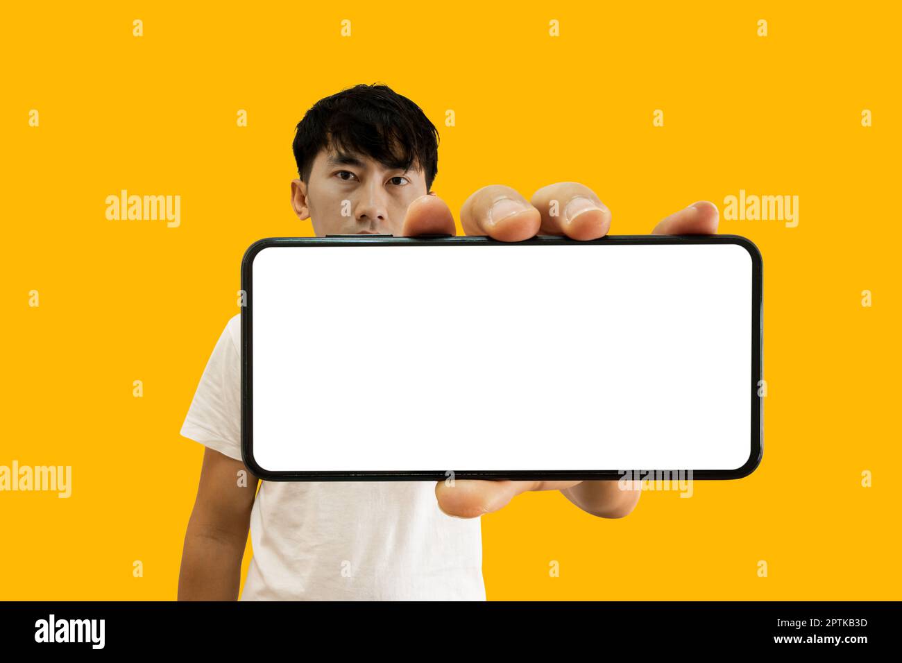 Asian Man tenant un smartphone avec écran blanc vide sur fond jaune. Maquette d'affichage de téléphone portable pour publicité d'application mobile. Banque D'Images