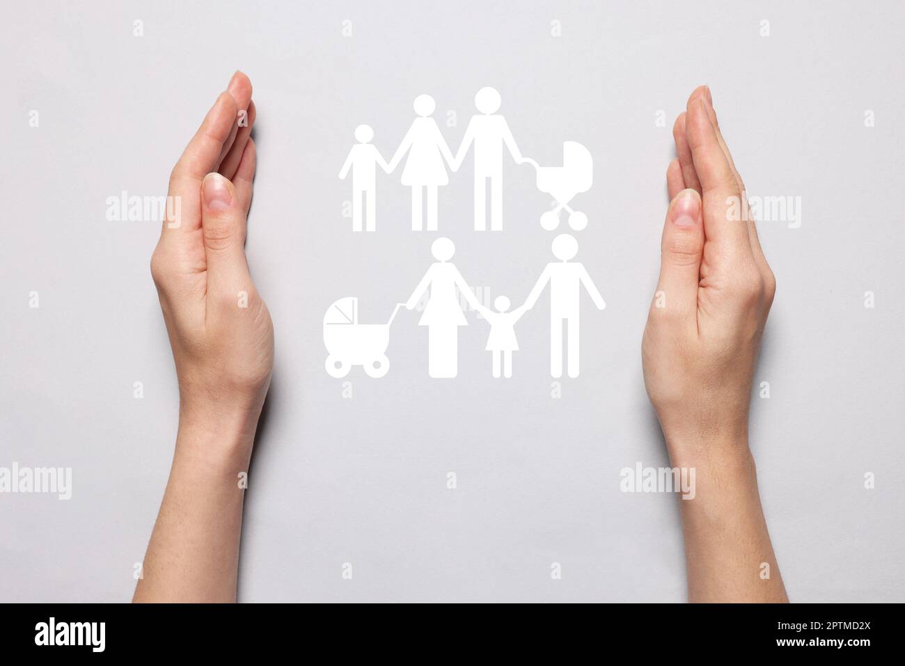 Femme tenant les mains autour de la silhouette de papier découpé des familles sur fond gris clair, vue de dessus. Concept d'assurance Banque D'Images