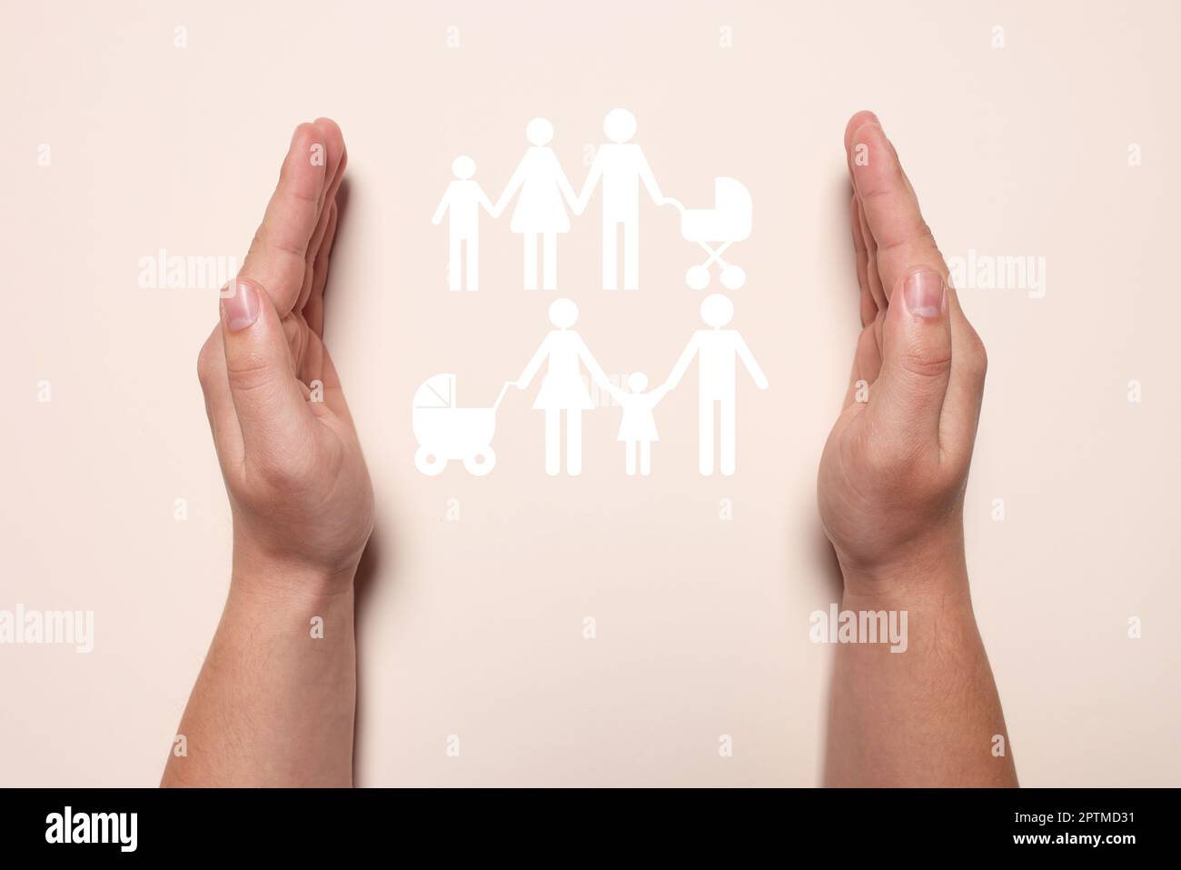 Homme tenant les mains autour de la silhouette de papier découpé des familles sur fond beige, vue du dessus. Concept d'assurance Banque D'Images