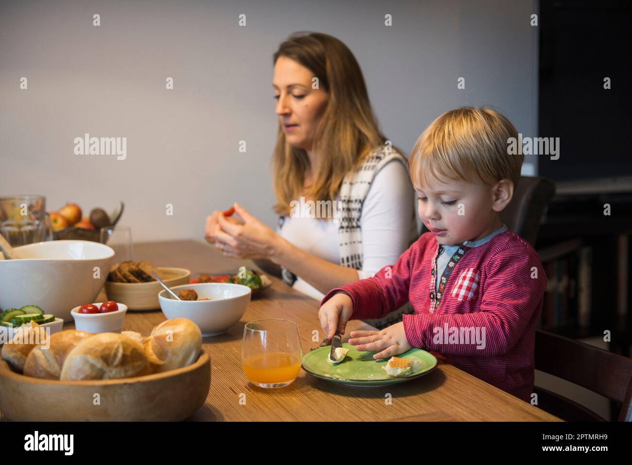 Un petit garçon qui se maque du beurre sur du pain, Munich, Allemagne Banque D'Images