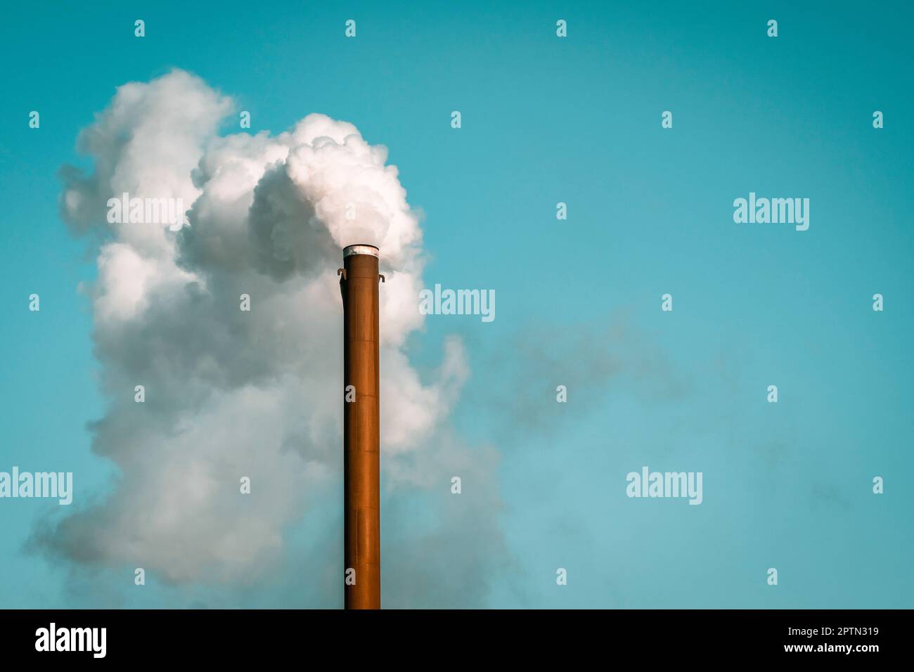 Concept de pollution mondiale. Cheminée d'usine soufflant de la fumée blanche du tuyau sur fond bleu ciel pendant l'hiver Banque D'Images