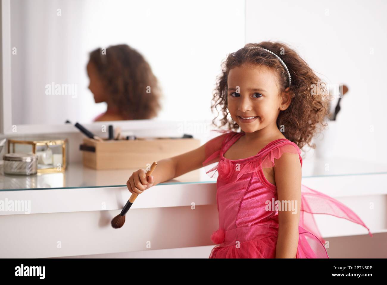 Je vais ressembler à ma maman. Portrait d'une petite fille jouant avec maquillage devant le miroir Banque D'Images