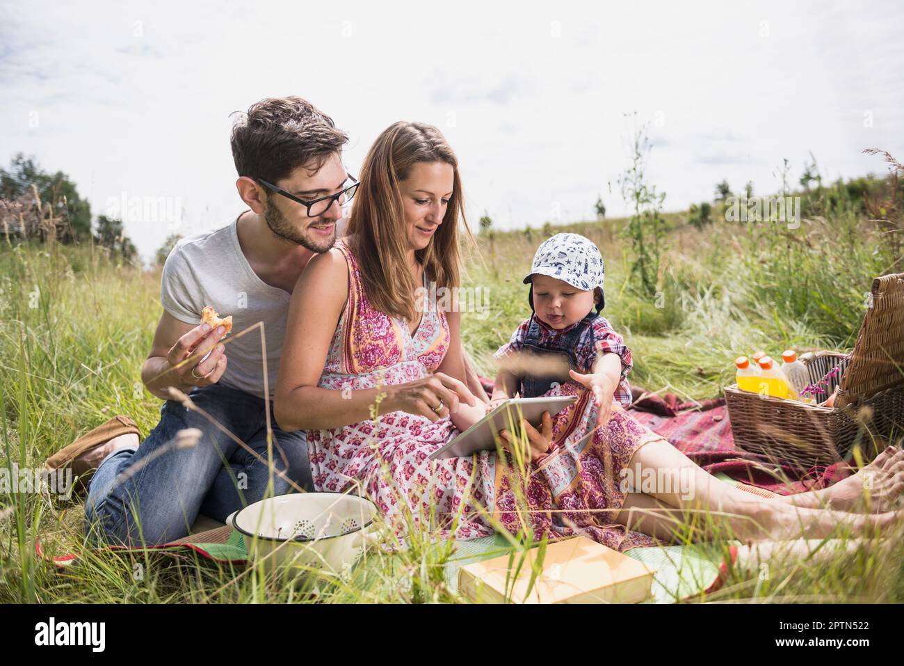 Famille utilisant la tablette numérique sur la prairie dans la campagne, Bavière, Allemagne Banque D'Images