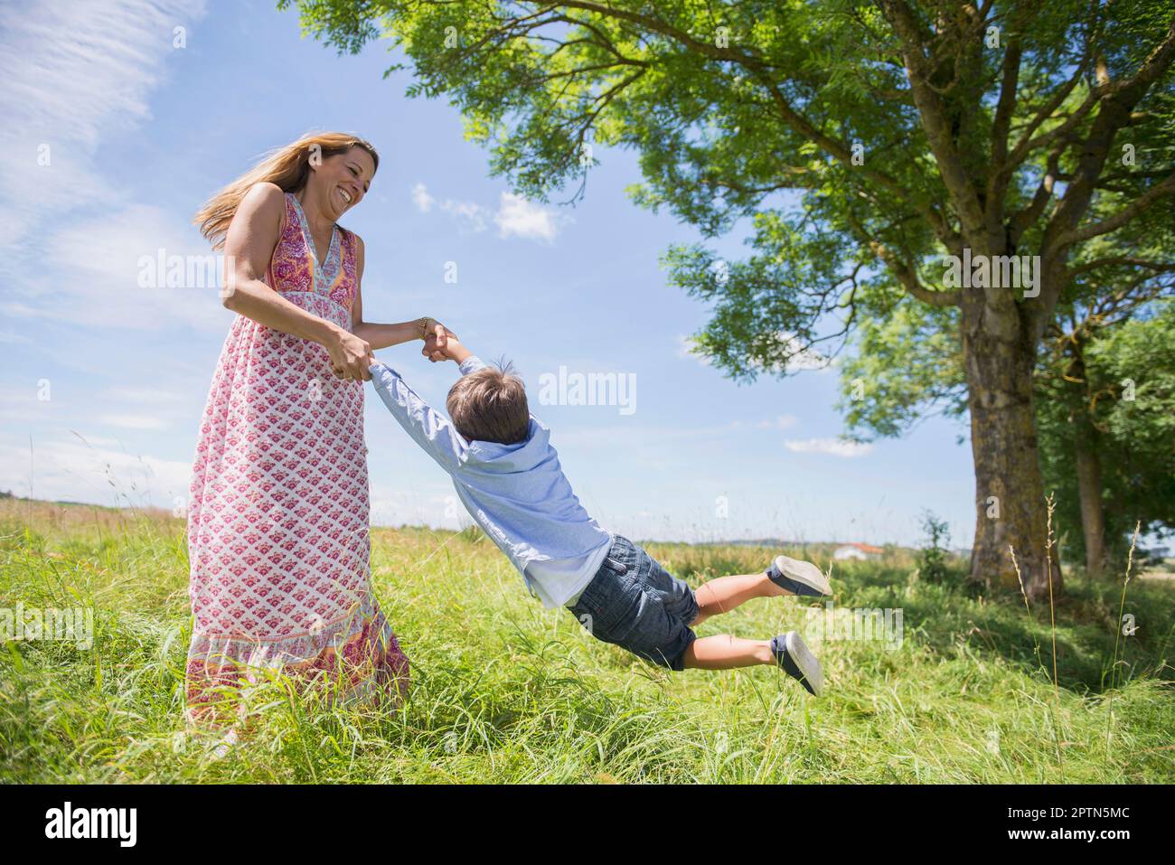 Femme balançoire garçon sur prairie dans pique-nique, Bavière, Allemagne Banque D'Images