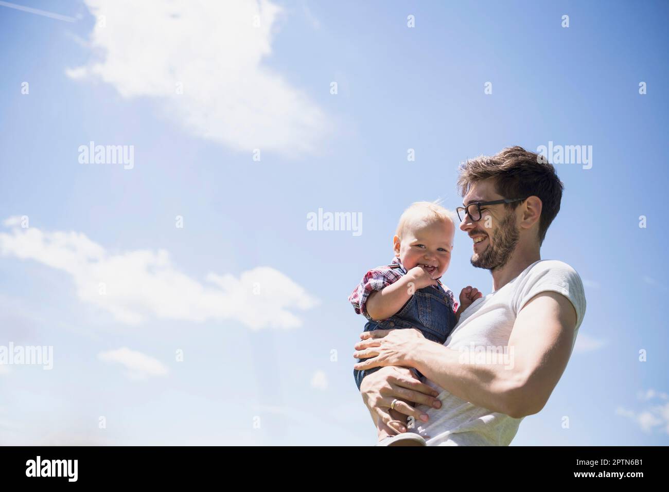 Heureux homme portant son fils contre le ciel, Bavière, Allemagne Banque D'Images