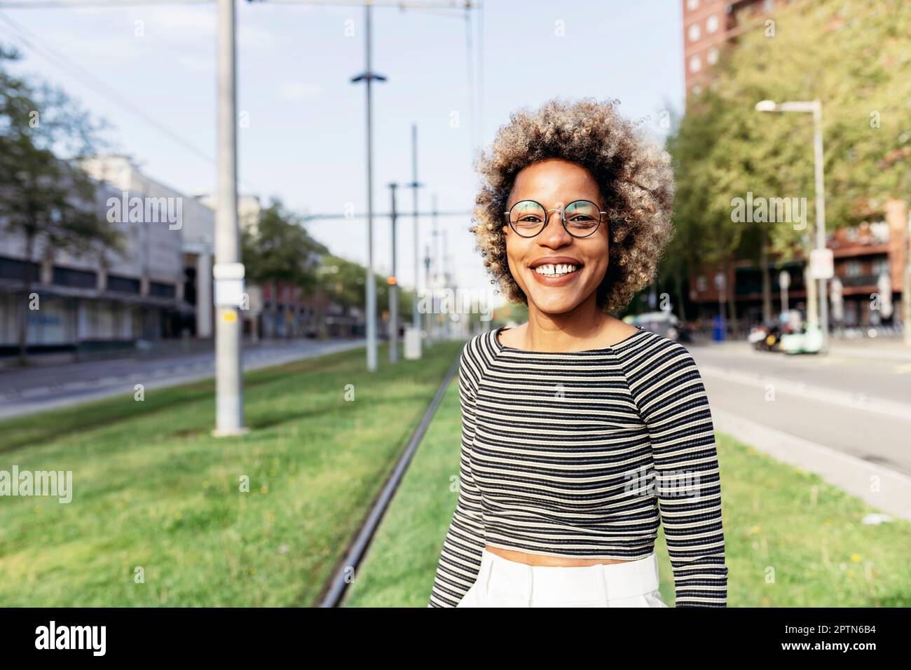 Portrait d'une femme afro-américaine posant dans la rue avec un pantalon blanc Banque D'Images