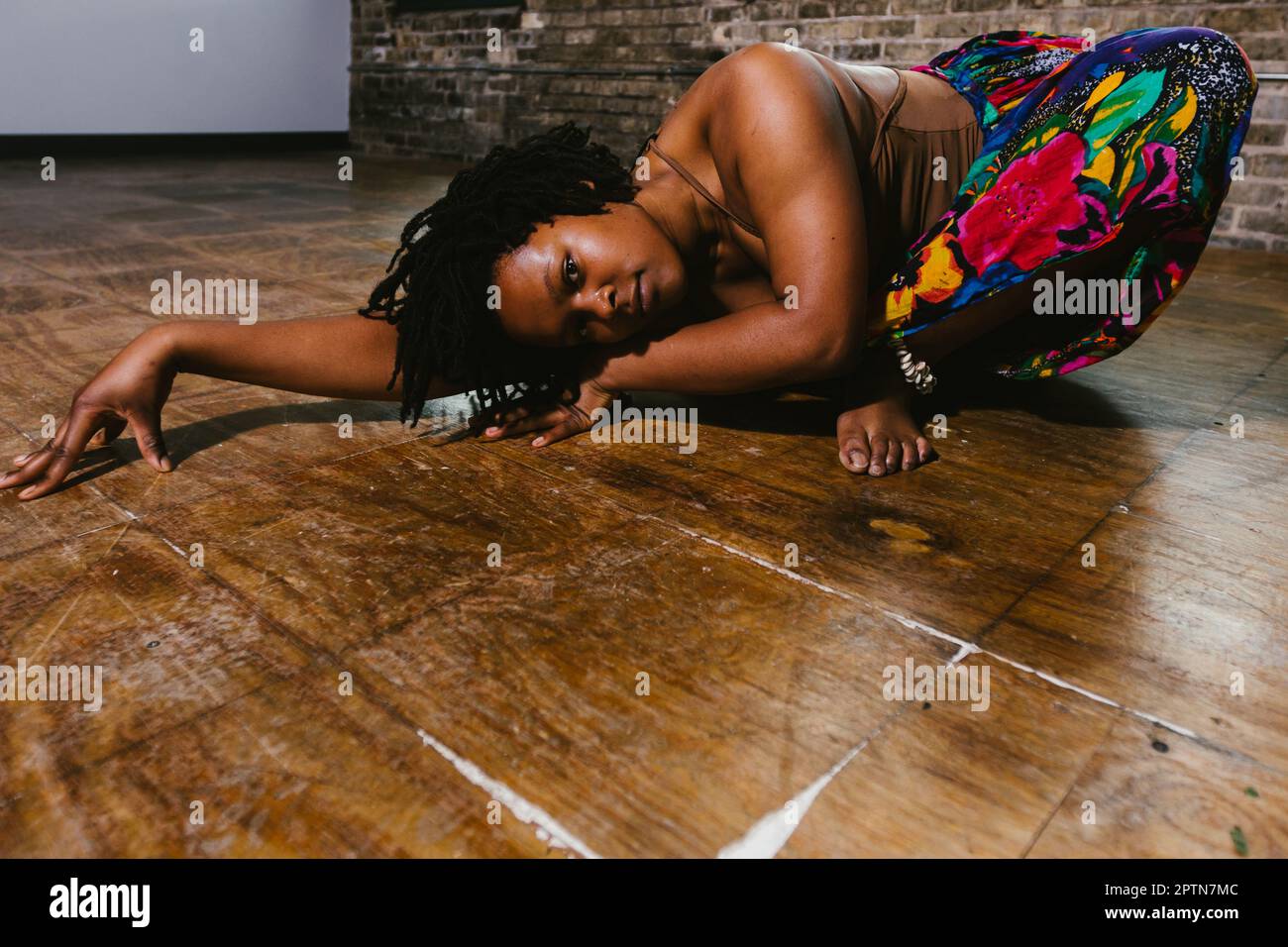 La danseuse contemporaine noire se déplace sur le sol avec une jupe colorée Banque D'Images