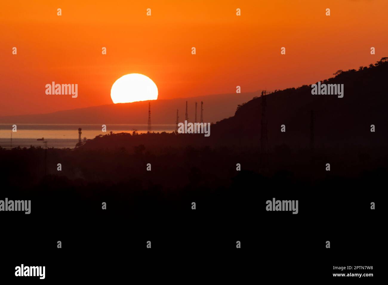Soleil levant derrière la montagne au-dessus de l'océan en Indonésie Banque D'Images