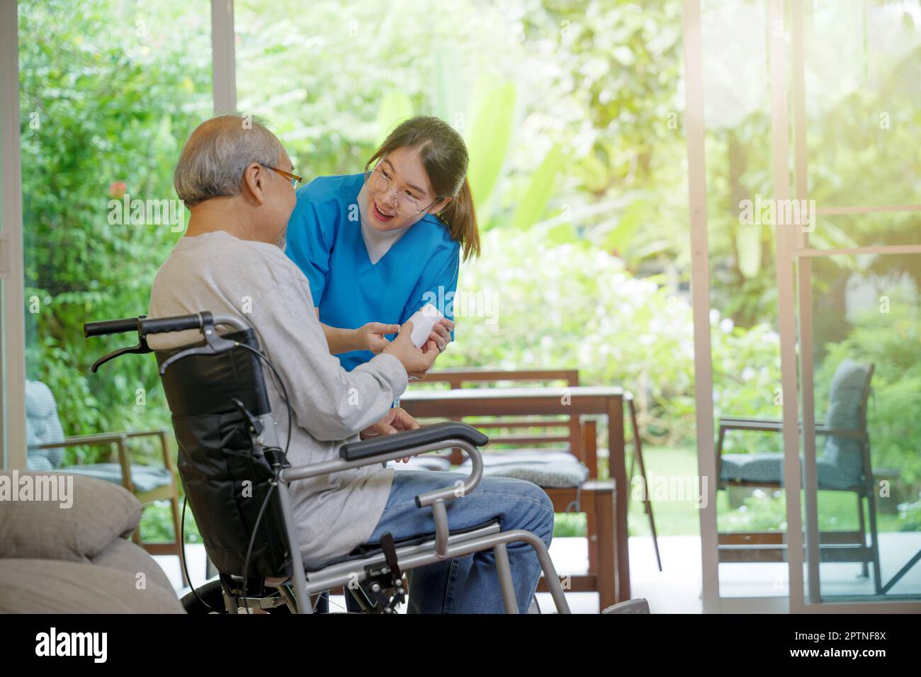 Les pilules d'infirmière de jeune femme asiatique avec l'aide prescrit des médicaments aux patients handicapés plus âgés sur fauteuil roulant lorsque le patient d'homme âgé a le temps de rentrer à la maison Banque D'Images