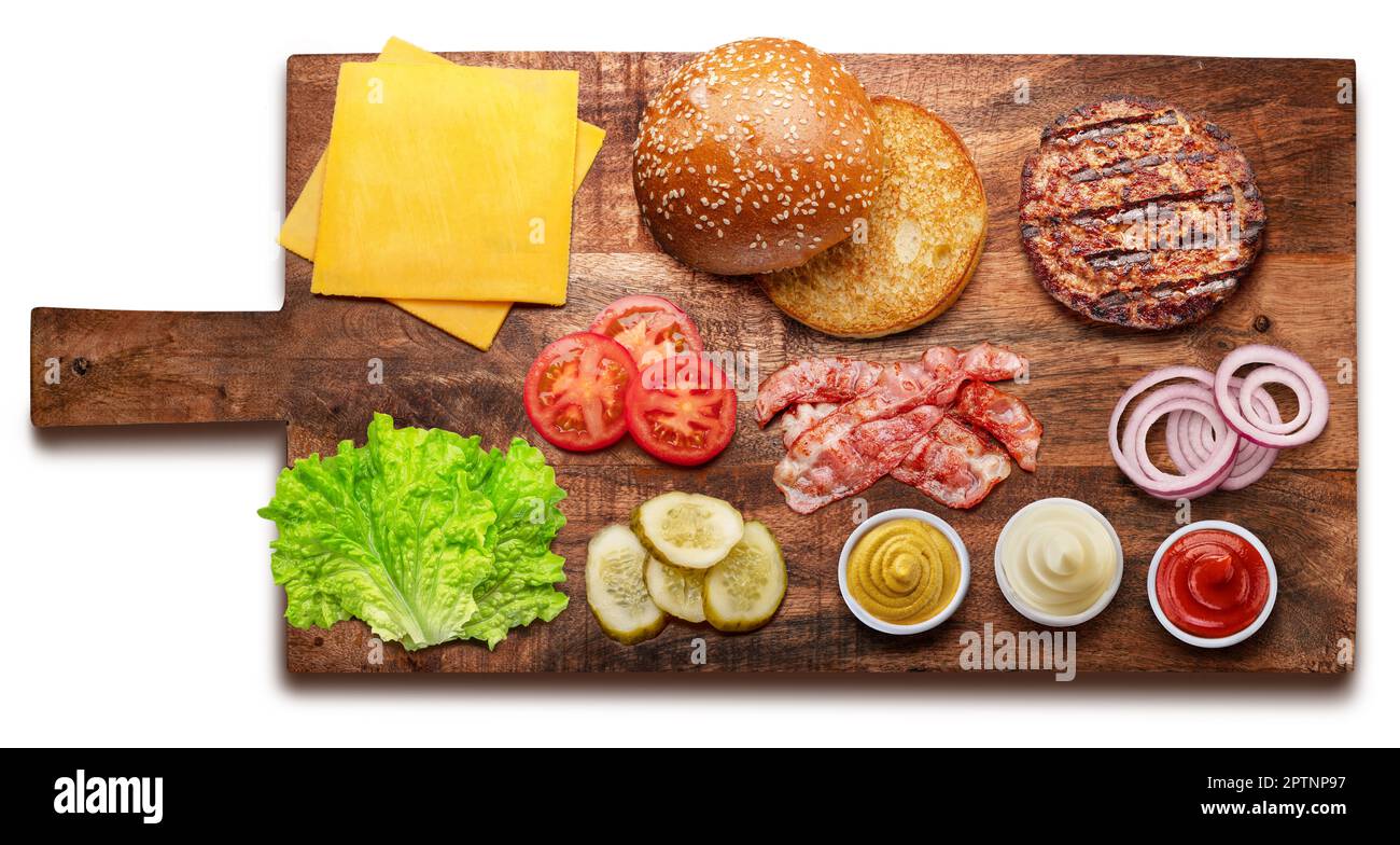 Ingrédients de cheeseburger ou de hamburger sur une planche de bois. Le fichier contient un chemin d'écrêtage. Pose à plat. Banque D'Images