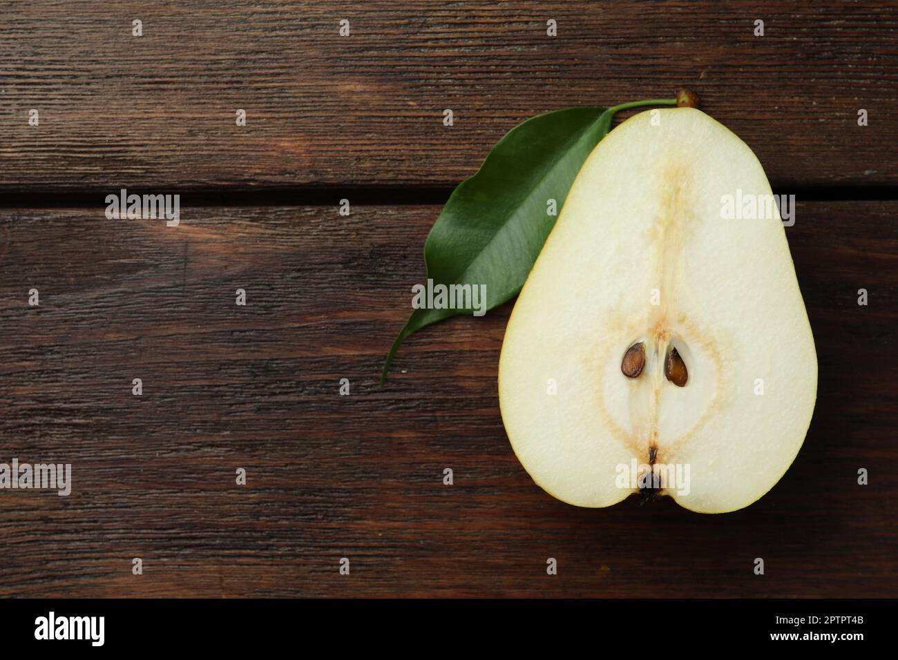 Moitié de poire fraîche savoureuse sur une table en bois, vue sur le dessus. Espace pour le texte Banque D'Images