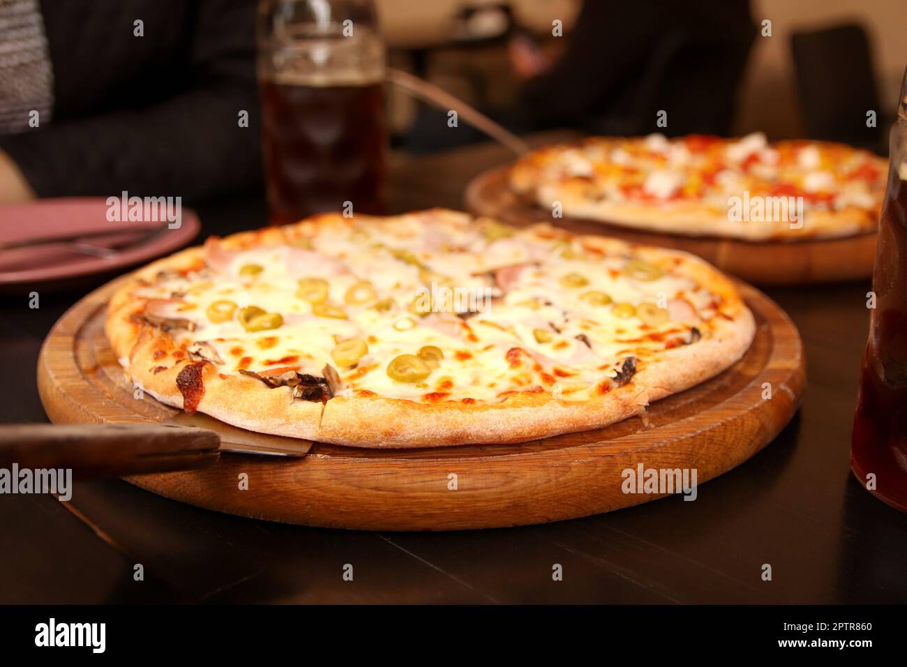 Pizza aux olives, basilic et fromage en gros plan. Pizzeria à l'extérieur. Refocalisation sur le fond de la pizza italienne avec des olives vertes sur la table. Tortilla avec Banque D'Images