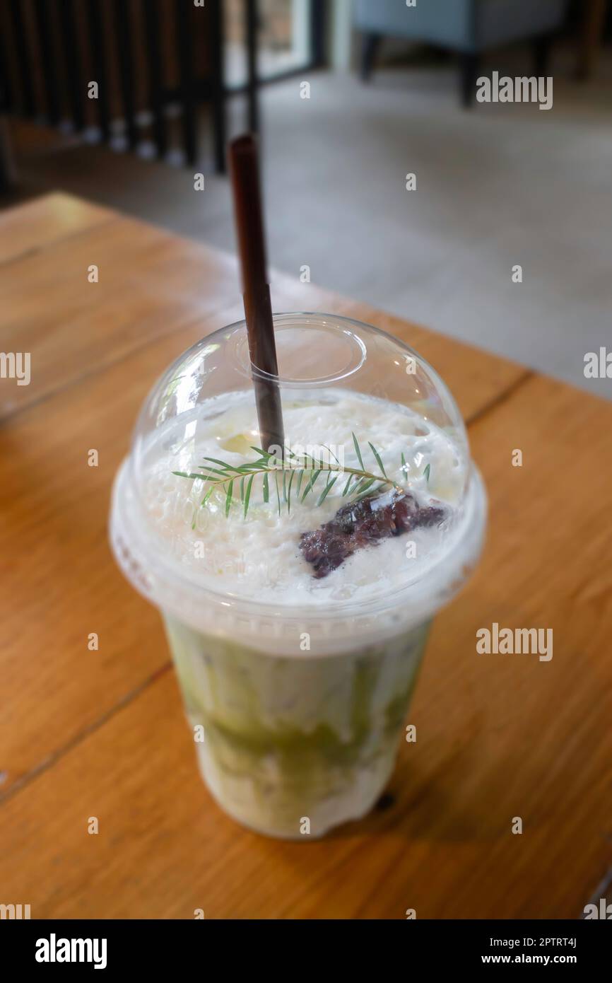 Thé vert glacé avec lait dans une tasse en plastique sur une table en bois, photo de stock Banque D'Images