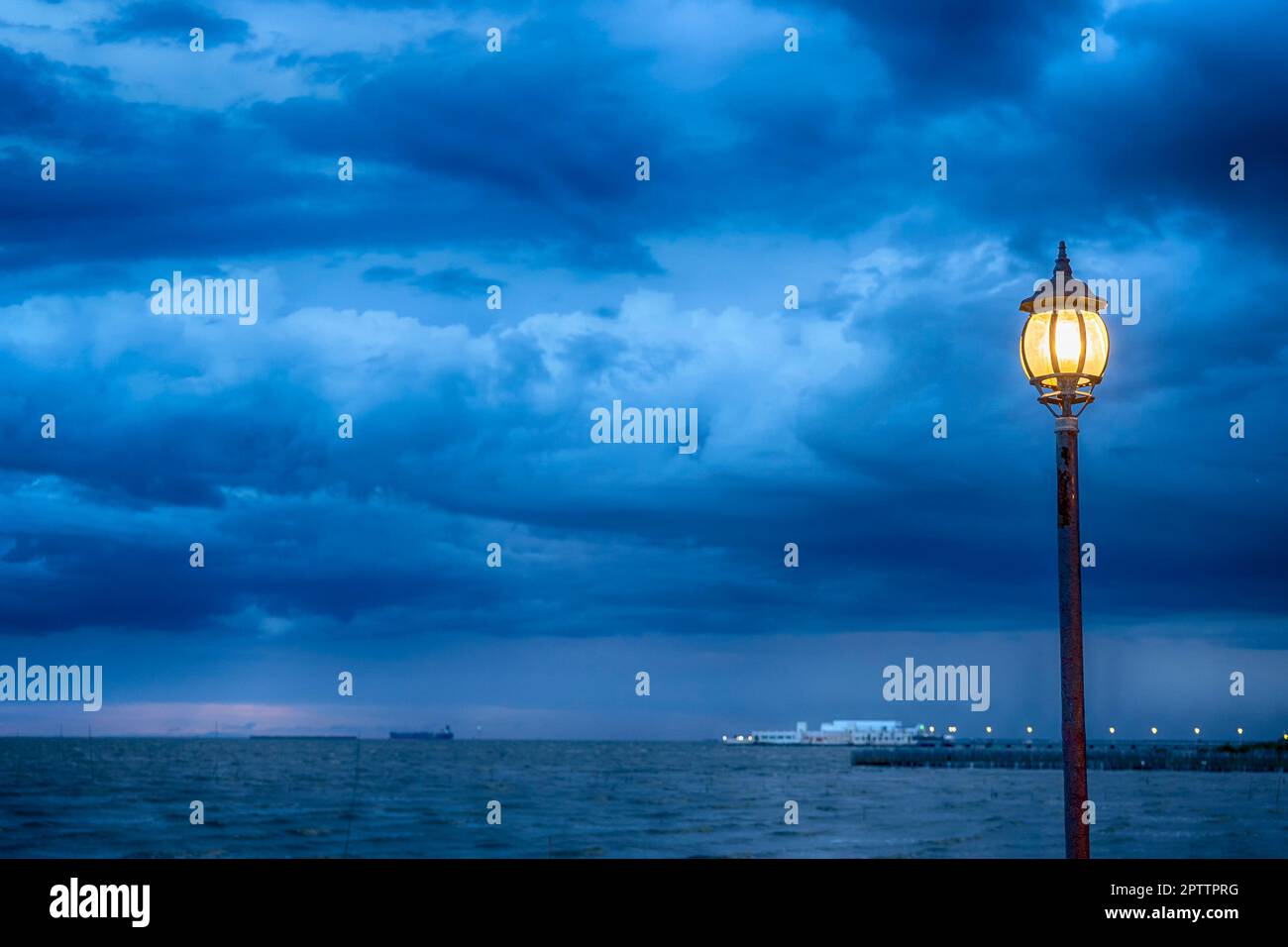 Poste de lumière au nigth près de la mer avec fond de stom Banque D'Images