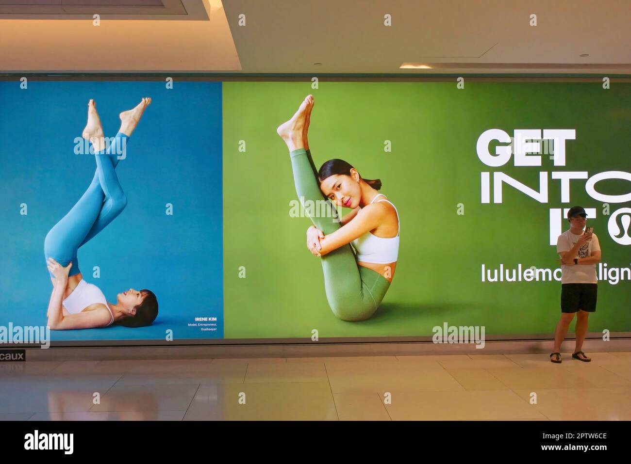 À ION Orchard (centre commercial), Orchard Road, Singapour, un jeune homme se tient devant les publicités sur le thème du yoga pour co. « Lulululemon » qui vend des vêtements de sport Banque D'Images